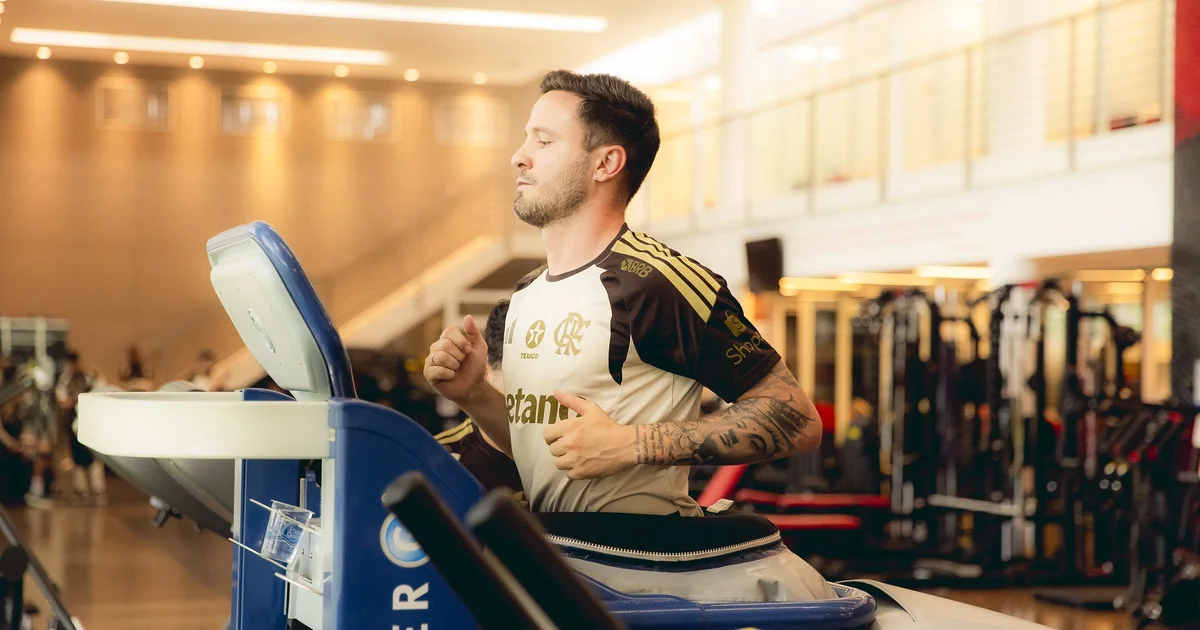 Jogador em recuperação no Ninho do Urubu: treino leve com fisioterapeuta e tornozelo enfaixado, foco na recuperação do Flamengo.