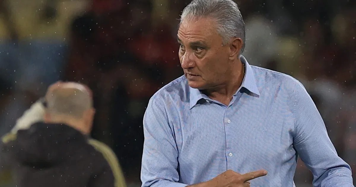 Técnico angustiado à beira do campo no Campeonato Brasileiro, placar 0-2 ao fundo e torcida tensa no estádio