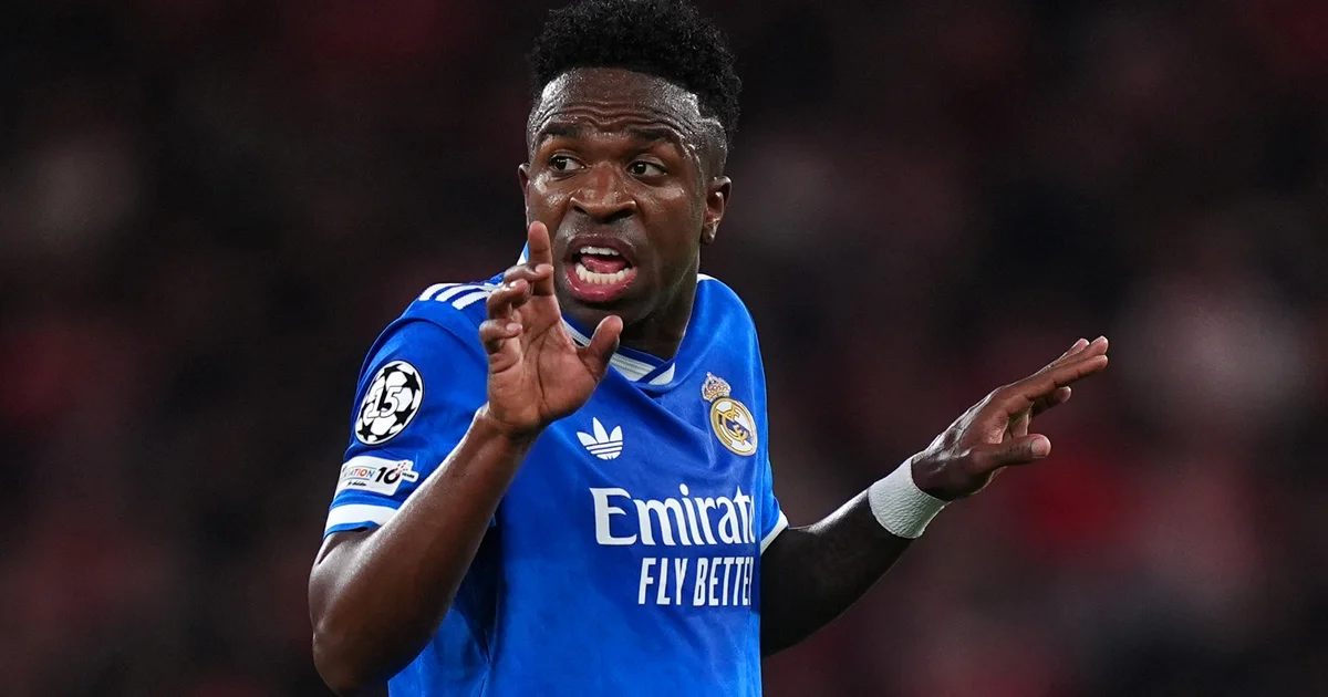 Ilustração editorial: jogador negro em estádio reage a racismo; árbitro aciona protocolo antirracista simbólico rasgado, multidão tensa.